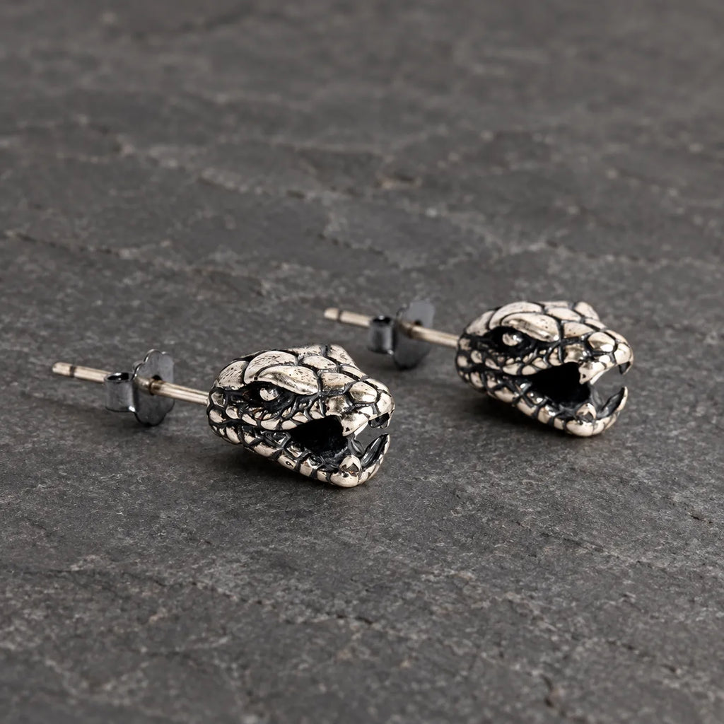 Three-quarter view of serpent head stud earrings showing their open jaws and sculptural depth