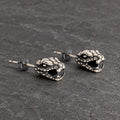 Three-quarter view of serpent head stud earrings showing their open jaws and sculptural depth
