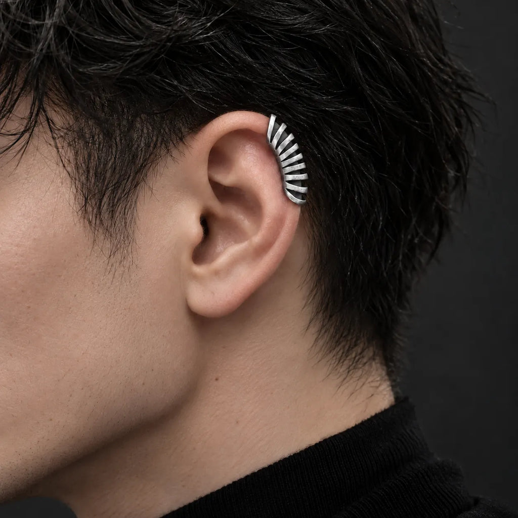 Oxidized sterling silver skeletal rib ear cuff worn on the upper helix of a dark-haired male model