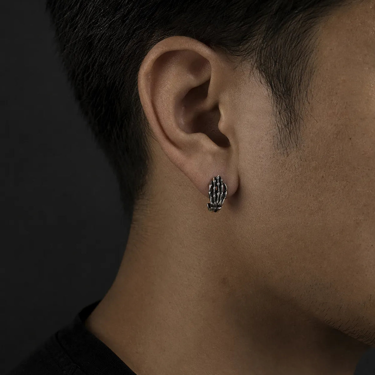 Skeleton hand stud earring worn on an ear to show its 8 × 16 mm size
