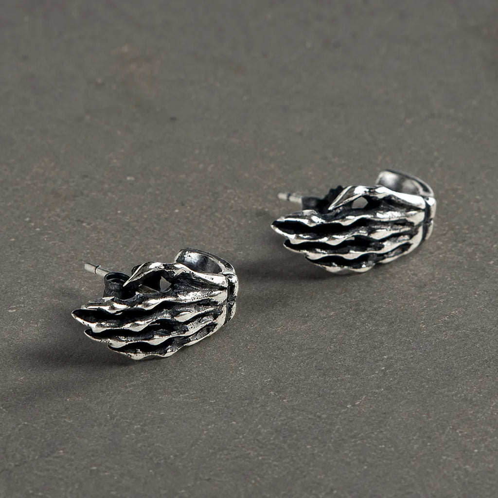 Pair of oxidized 925 sterling silver skeleton hand stud earrings on dark stone