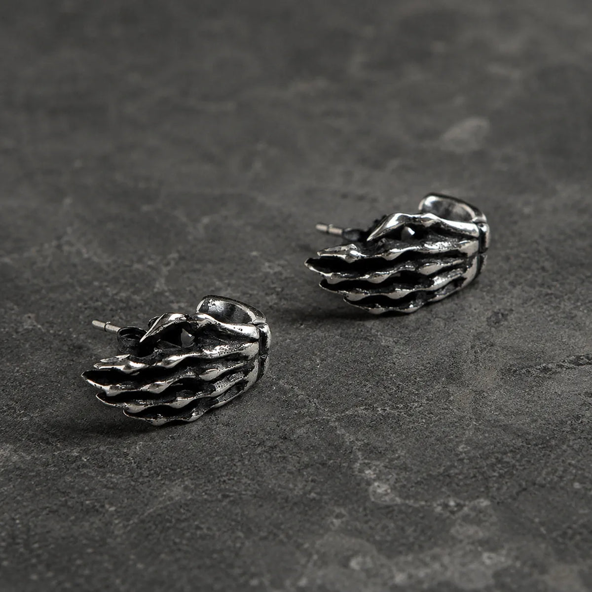 Side view of skeleton hand stud earrings showing their curved shape and straight posts