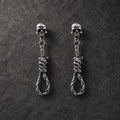 Pair of oxidized 925 sterling silver skull and noose dangle stud earrings on dark stone