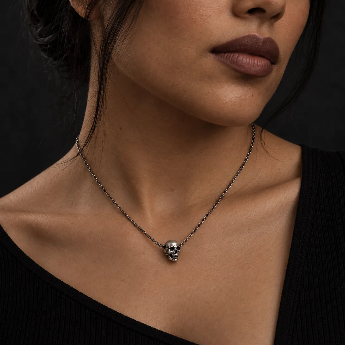 Latina model wearing the No. 3 articulated skull pendant at its actual 9 by 10 mm size on a 1.5 mm chain