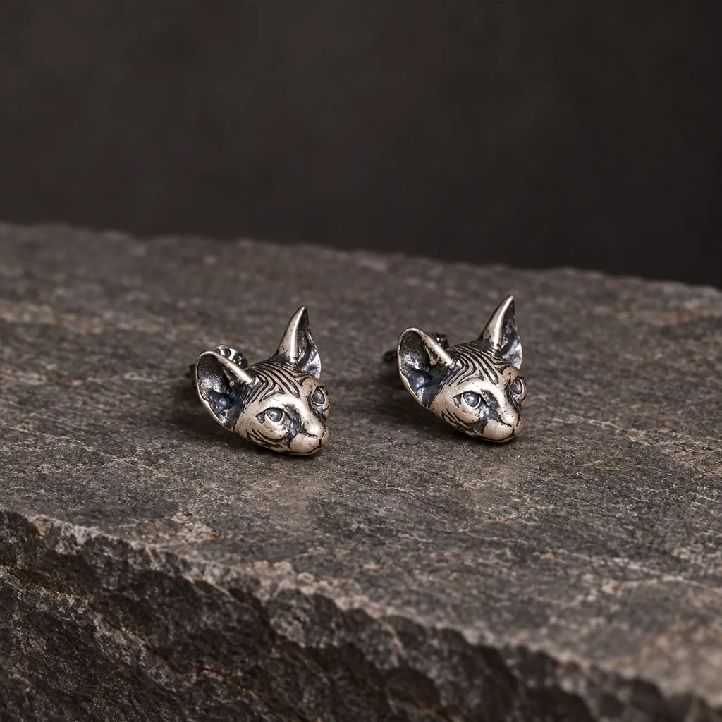 Low angled view of silver Sphynx cat earrings showing their sculptural depth