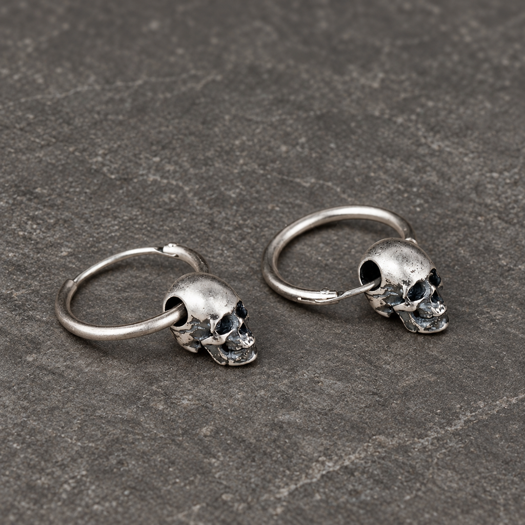 Angled view of sterling silver skull hoop earrings showing their curved wire construction
