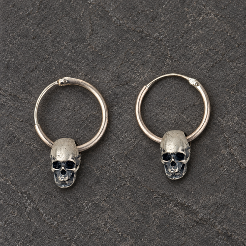 Pair of oxidized sterling silver skull hoop earrings shown from the front