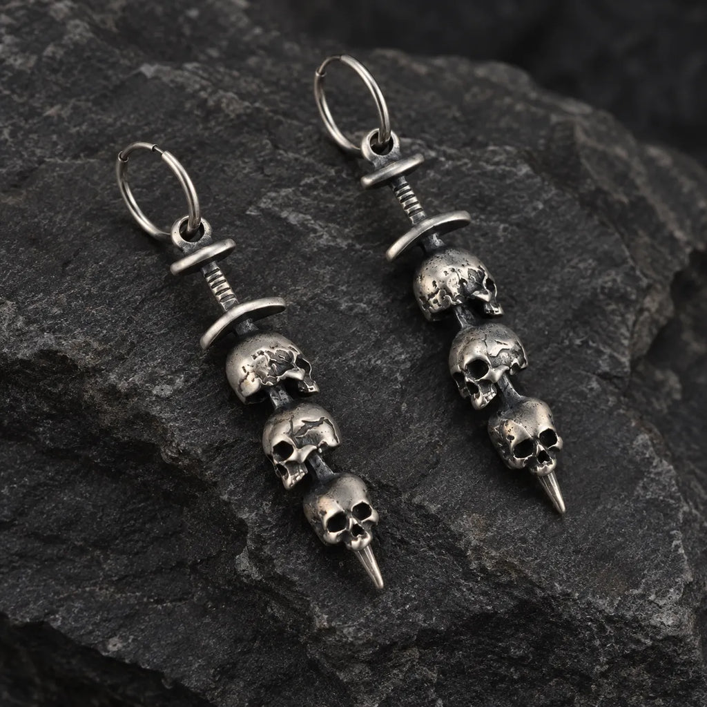 Angled view of triple skull sword earrings showing their sculptural depth and wire hoops