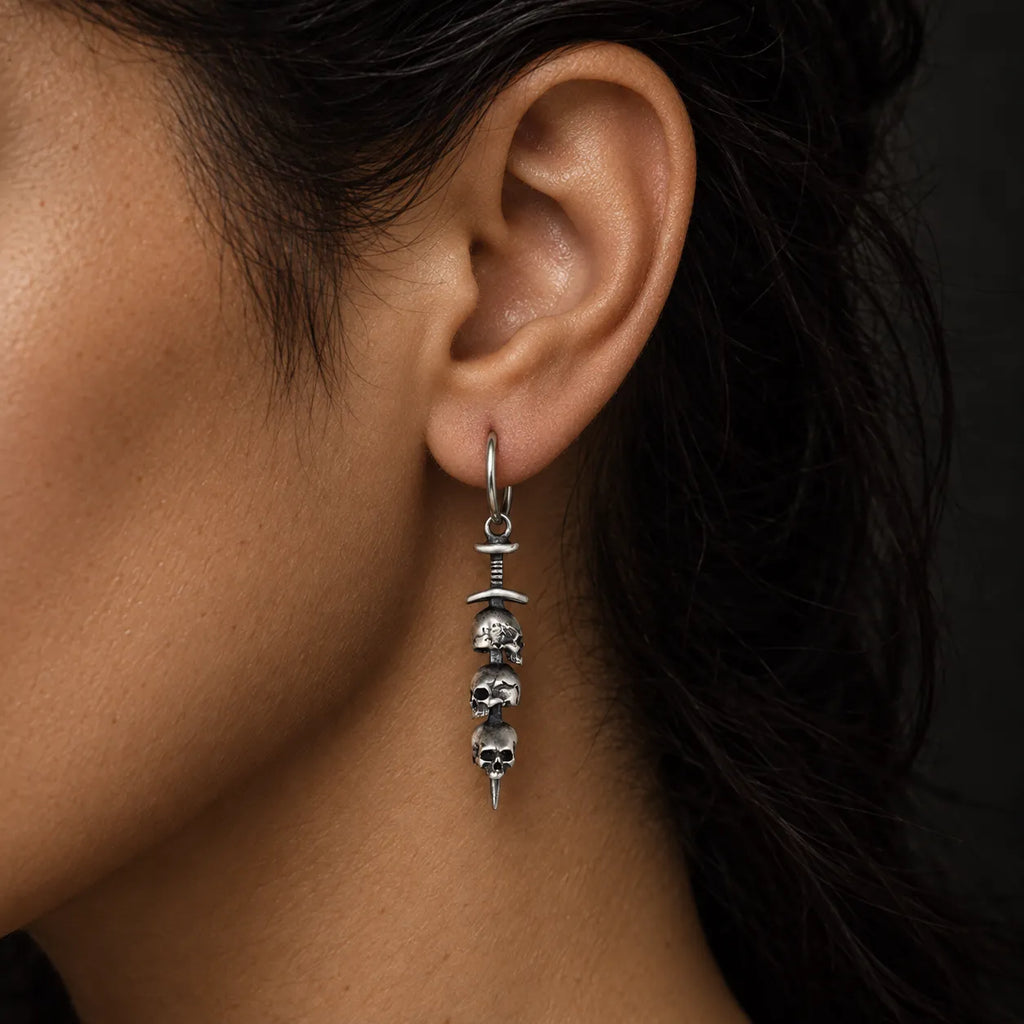 Close-up of a woman wearing a triple skull sword hoop earring to show its scale